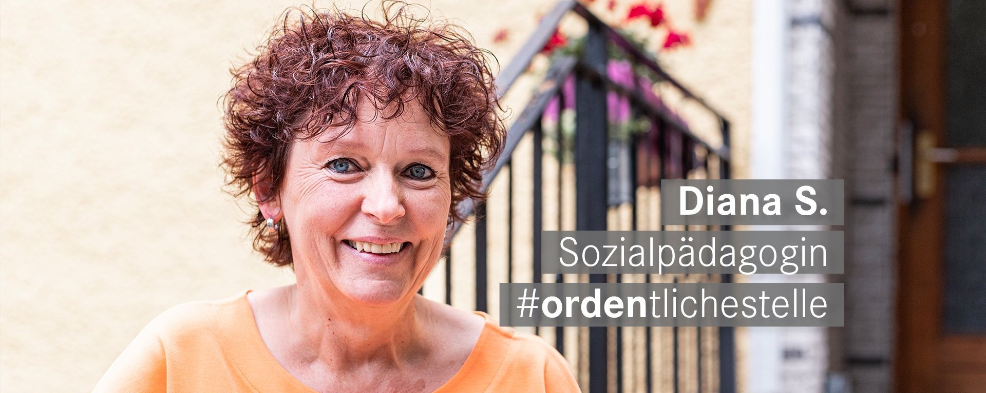 Sozialpaedagogin mit roten kurzen Locken und blauen Augen laechelt freundlich in die Kamera