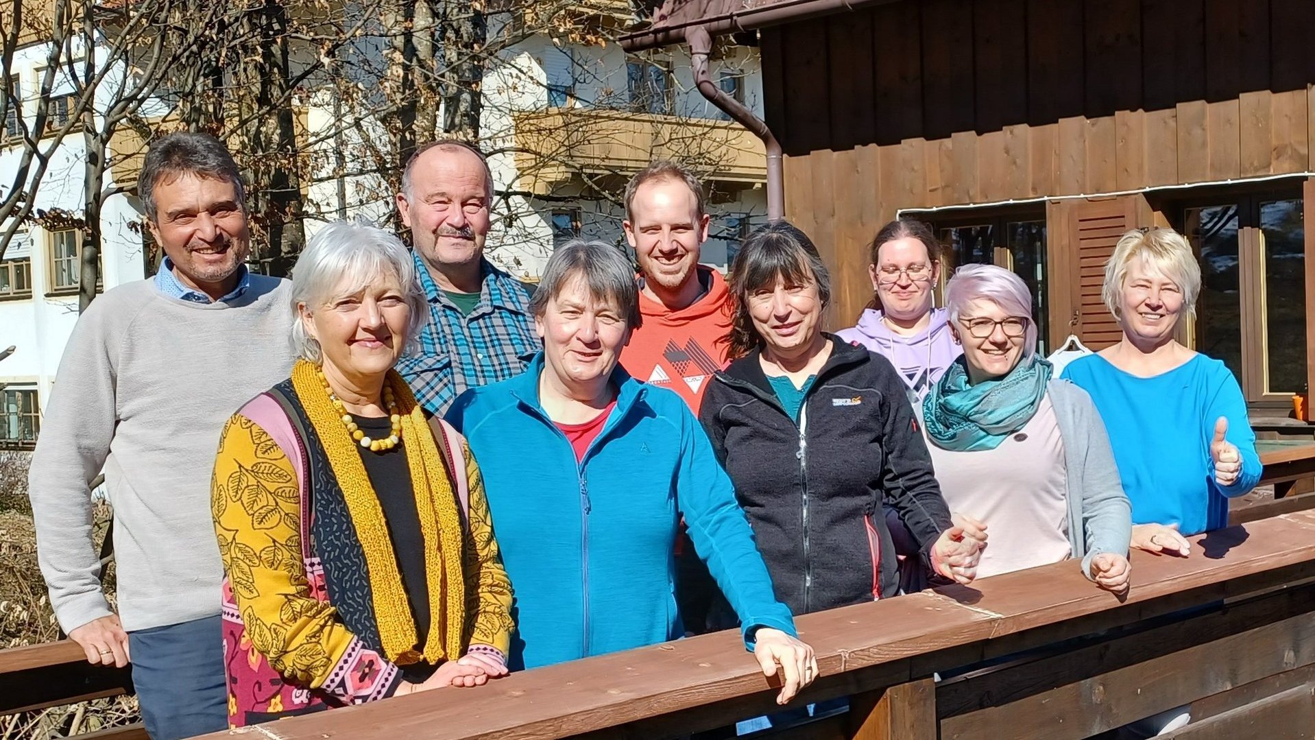 Eine Gruppe von neun Leuten hat sich für ein Gruppenfoto aufgestellt. Alle lächeln in die Kamera.