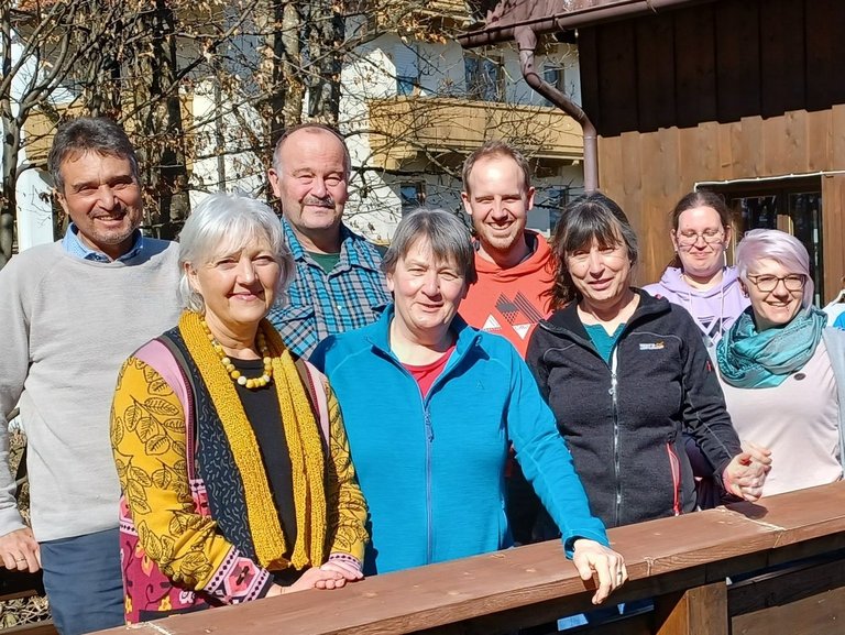 Eine Gruppe von neun Leuten hat sich für ein Gruppenfoto aufgestellt. Alle lächeln in die Kamera.