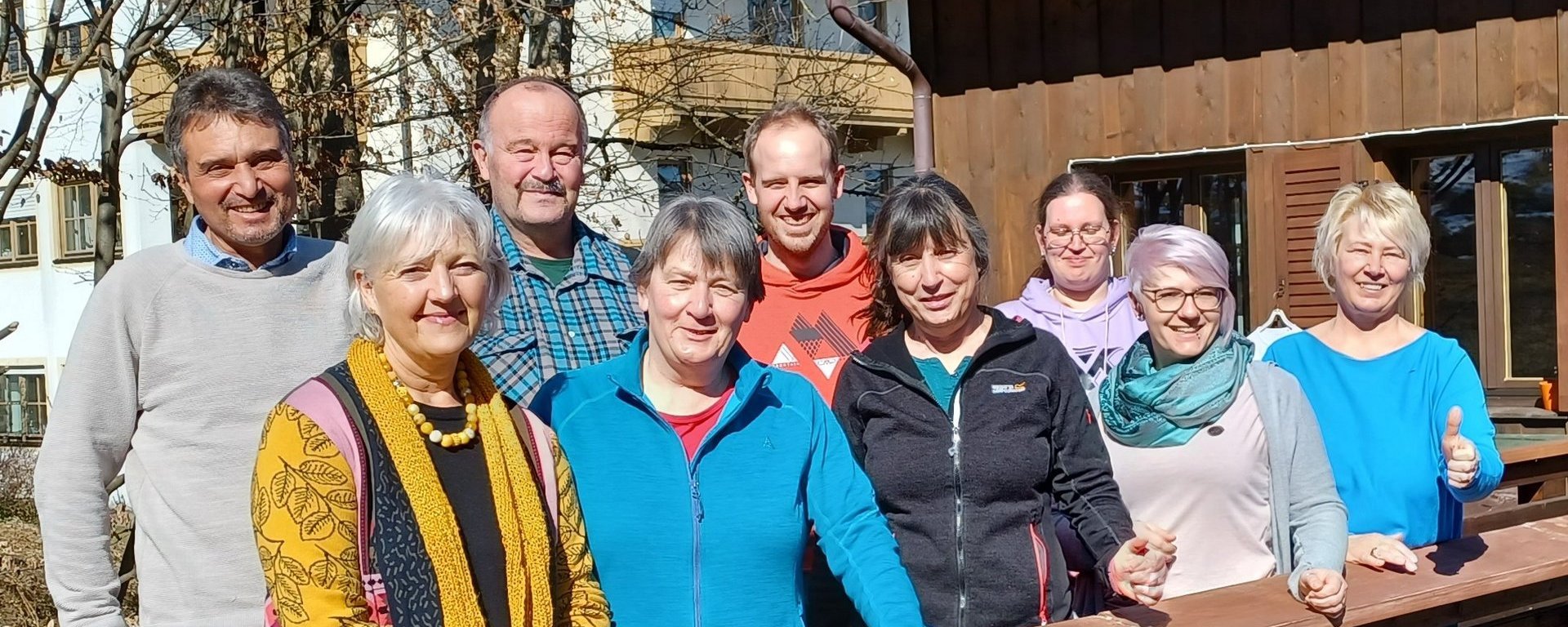 Eine Gruppe von neun Leuten hat sich für ein Gruppenfoto aufgestellt. Alle lächeln in die Kamera.