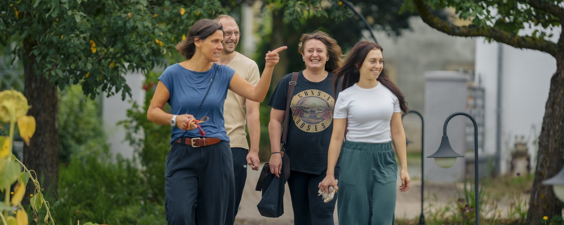 drei Frauen und ein Mann gehen zusammen draussen spazieren 